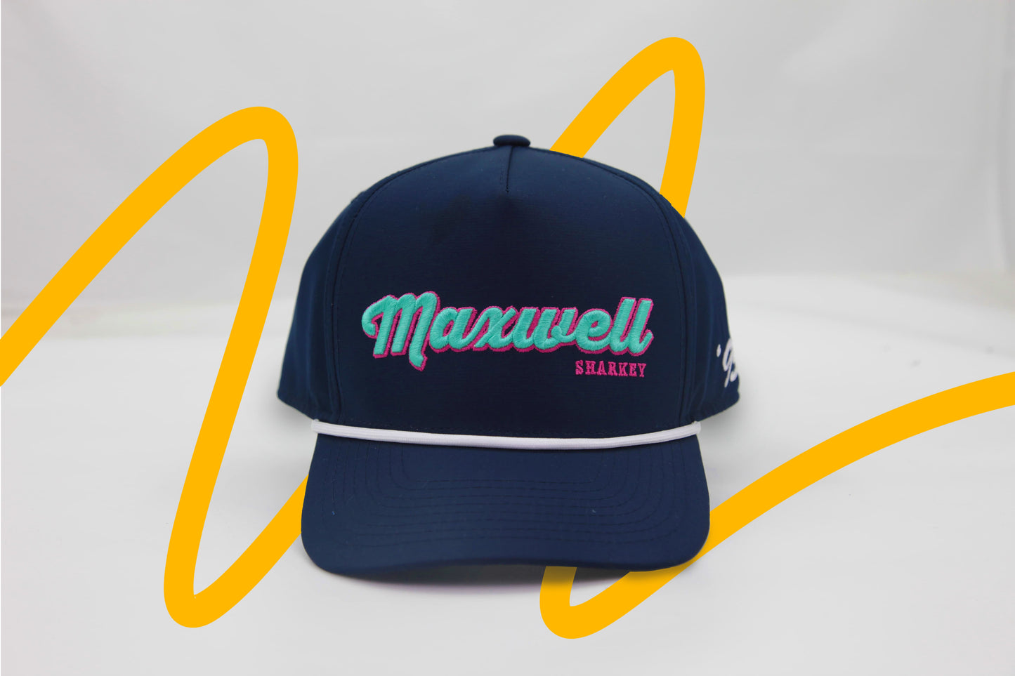 Front view of The Midnight Cruiser ’93 Hat – navy cap with Maxwell Sharkey embroidered on the front in teal and pink, in a vintage cursive font. There is a white rope detail across the brim.