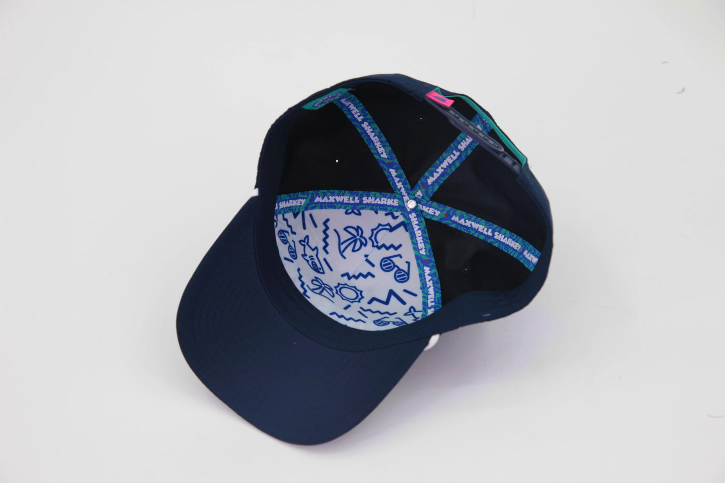 Underbrim view of The Midnight Cruiser ’93 Hat – navy interior with blue and white signature Maxwell Sharkey pattern. The hat is lined with a funky teal and blue taping displaying Maxwell Sharkey in a chunky, fun font.