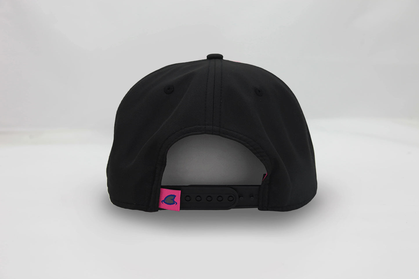 Back view of The Neon Lights Hat – black cap with a pink embroidered loop tag featuring the Maxwell Sharkey fin icon with an adjustable snapback closure.