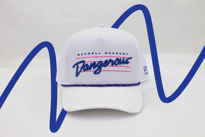 Front view of The Dangerous ’93 Hat – bright white hat with retro “Dangerous” logo in bold blue script and pink background lines, with Maxwell Sharkey in small print above the script. It features a blue and pink rope detail across the brim.