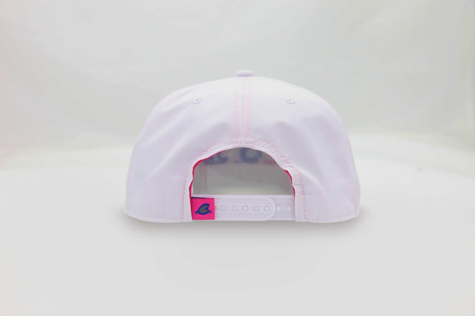 Back view of The Ice Dangerous ’93 Hat – white cap with adjustable strap and small, pink loop tag accent featuring the Maxwell Sharkey shark fin icon.