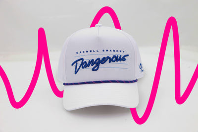 Front view of The Ice Dangerous ’93 Hat – a bright white cap embroidered with “Dangerous” script in blue over aqua lines in the background. Maxwell Sharkey is in small print above the script. It features blue and pink rope detail across the brim.