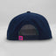 Back view of The Midnight Cruiser ’93 Hat – navy blue cap with snapback closure and small pink loop tag featuring the Maxwell Sharkey fin icon.