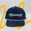 Front view of The Midnight Cruiser ’93 Hat – navy cap with Maxwell Sharkey embroidered on the front in teal and pink, in a vintage cursive font. There is a white rope detail across the brim.