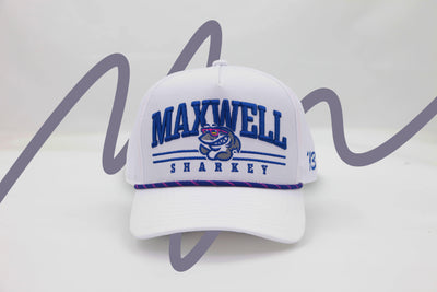 Front view of The Shark Attack Rope Hat – a bright white baseball cap embroidered with the Maxwell Sharkey mascot logo amidst bold, slab-serif letters reading "Maxwell Sharkey". It features a blue and pink rope detail across the brim.