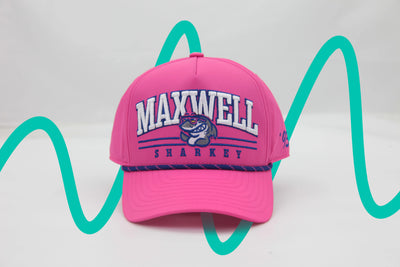 Front view of The Sunset Slasher ’93 Hat – hot pink rope hat with Maxwell Sharkey written in blue and white, and the Maxwell Sharkey mascot nestled between the words. The hat features a blue and pink rope detailing across the brim.