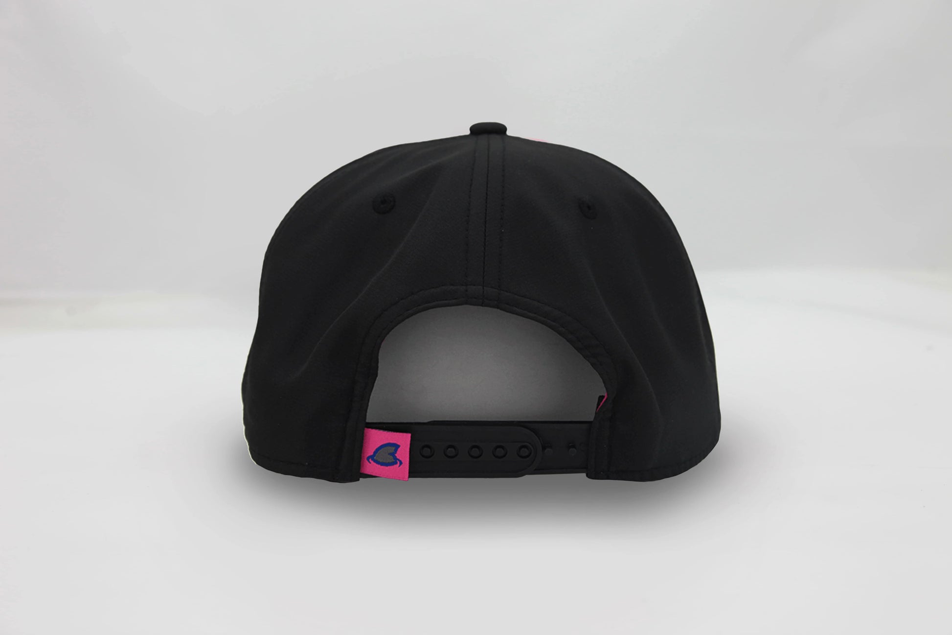 Back view of The Neon Lights Hat – black cap with a pink embroidered loop tag featuring the Maxwell Sharkey fin icon with an adjustable snapback closure.